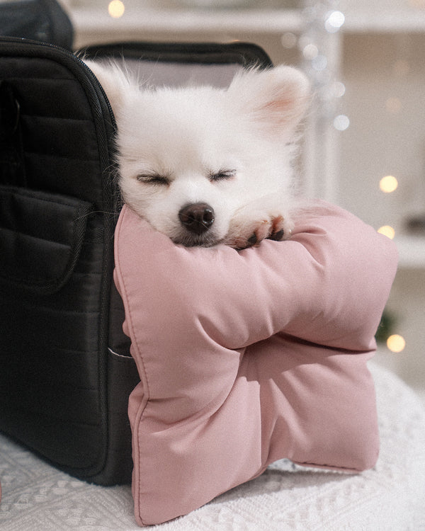 A fluffy white dog peacefully resting on a soft, pink, water-resistant Soycraft carrier cushion. Designed for maximum comfort and durability, this cushion adds a touch of luxury to your pet's travel experience.